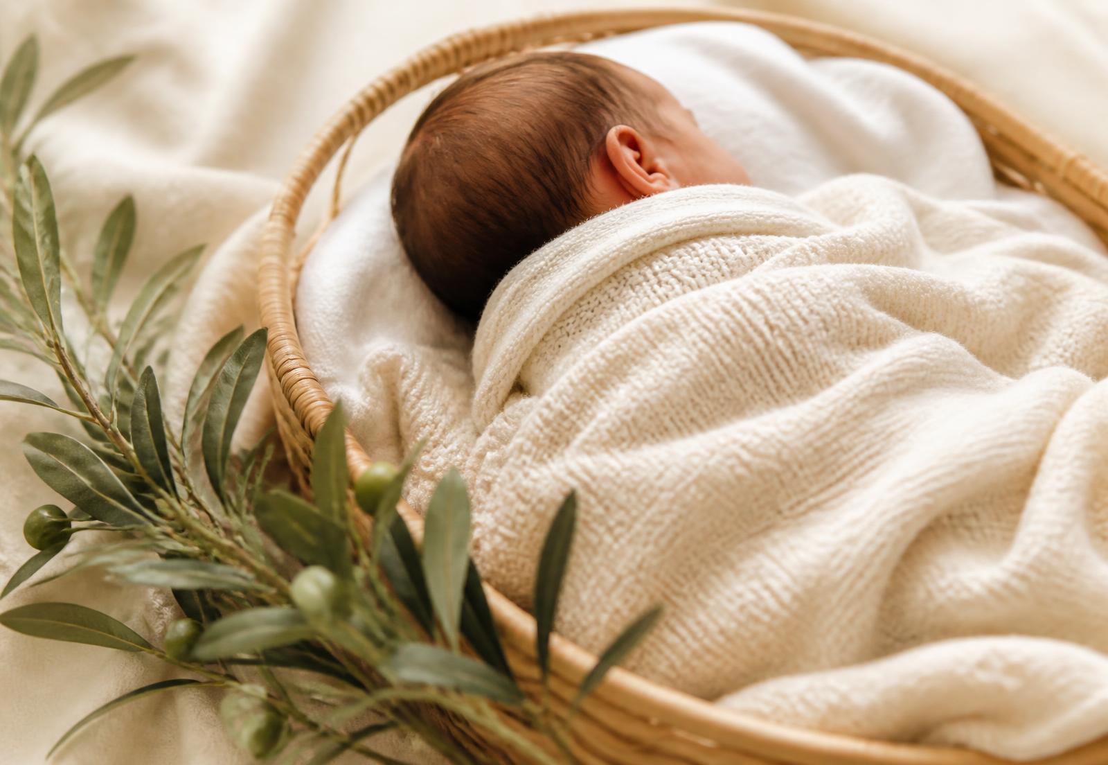 Newborn baby swaddled in a cream blanket